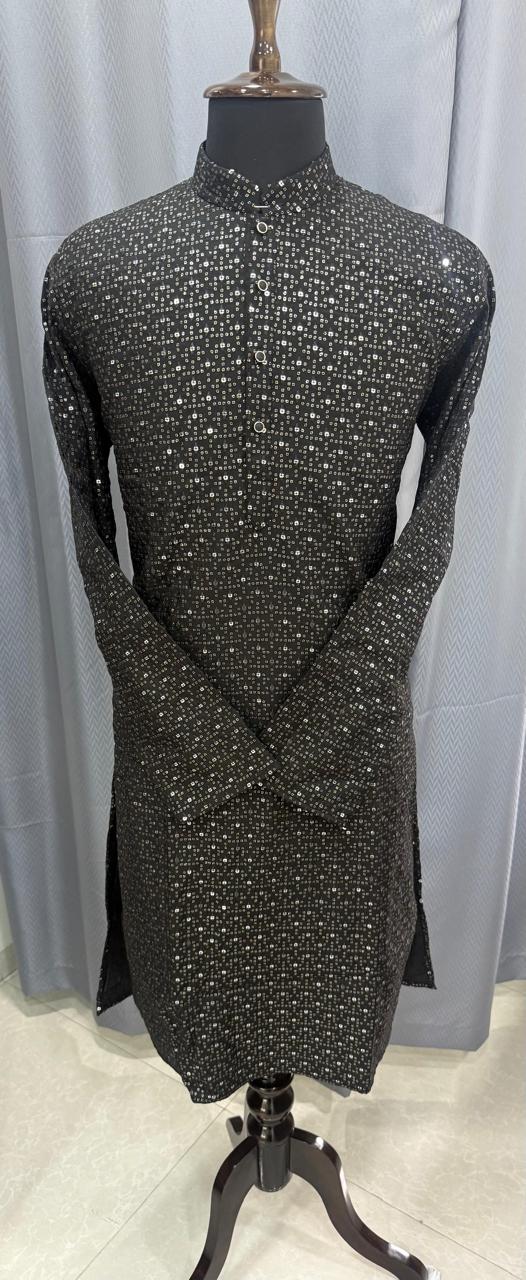 Mannequin wearing a black dress with white polka work sequence against a light gray curtain background